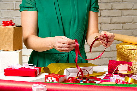 圣诞节和新年的礼品包装 手工制作的 女孩的手有礼品丝带 麻线 胶带和包裹的礼物 展示 女性图片