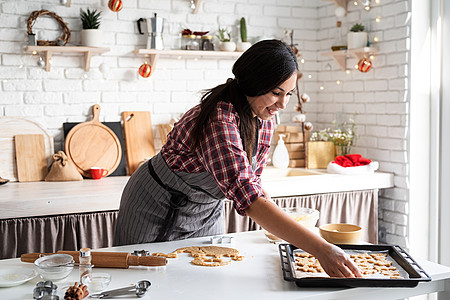 做糕点的女人在厨房做饼干的黑发年轻女人 正在厨房烤饼干 家庭主妇 姜饼背景