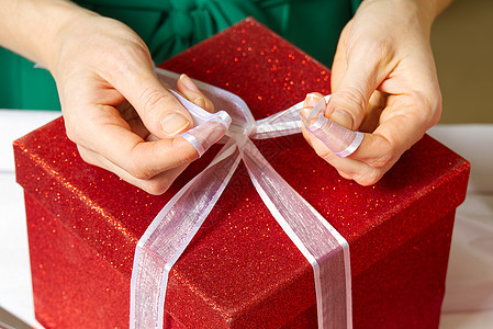 妇女用手将圣诞节礼物装在红色盒子中 带白丝带 假期 情人节图片