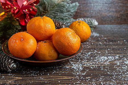 树枝和松锥上覆着雪 新年的构想是 在木制背景上的坦格林 Tangerines 有圣诞树枝和松果 热带 雪花图片