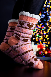 女人的腿穿着圣诞树附近的多彩袜子 冬天 取暖器图片
