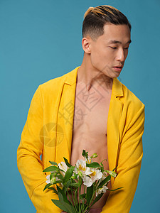 带白花和大衣裤前观的鲜花束束子的亚洲帅哥男子图片