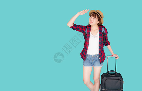 美丽的年轻亚洲女人拉着蓝色背景中突显的手提箱 有表情的亚洲女孩带着兴奋 旅行和旅行的概念快乐地拿着行李在假期中行走 快乐的 步行图片
