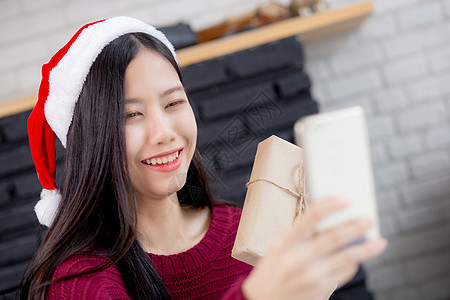 年轻的亚洲女性在网上与朋友进行自拍视频通话 并在圣诞节那天在家里的电话中展示礼品盒 社交距离 新常态 女性视频会议 沟通和假期概图片