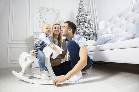 在圣诞节的家庭 爸爸妈妈和孩子在圣诞树的背景下玩耍 父母和儿子在新的一年 快乐的 男生图片