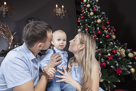 在圣诞节的家庭 爸爸妈妈和孩子在圣诞树的背景下玩耍 父母和儿子在新的一年 坐着 女孩图片