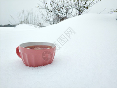 一个粉红杯子 在寒冬雪场背景上加热兰莓茶 寒冷的冬季有果酱和热味茶 极简主义 冻结图片