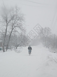 村里有雪雪暴 一个男人在街上骑自行车图片