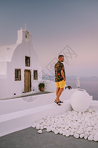 希腊圣托里尼岛日落 美丽的白洗的奥亚村 Oia 美丽 日落时有教堂和风车 青年男子在豪华度假 日出 奢华图片
