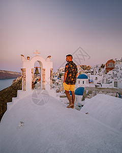 希腊圣托里尼岛日落 美丽的白洗的奥亚村 Oia 美丽 日落时有教堂和风车 青年男子在豪华度假 日出 建筑学图片