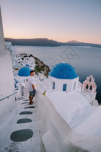 希腊圣托里尼岛日落 美丽的白洗的奥亚村 Oia 美丽 日落时有教堂和风车 青年男子在豪华度假 房子 村庄图片