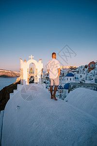 希腊圣托里尼岛日落 美丽的白洗的奥亚村 Oia 美丽 日落时有教堂和风车 青年男子在豪华度假 旅游 火山图片