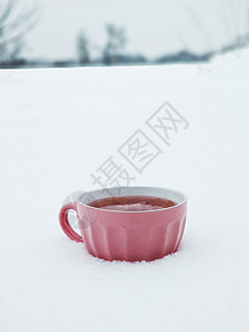 一个粉红杯子 在寒冬雪场背景上加热兰莓茶 寒冷的冬季有果酱和热味茶 极简主义 新年图片