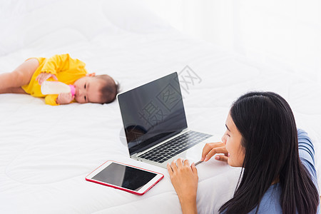 妇女在家里忙着用笔记本电脑和平板电脑工作 而婴儿正在睡觉 商业 新生图片