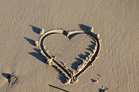 一个美丽的心形画在波罗的海海滩的沙子里 有一些水波 海浪 晴天图片