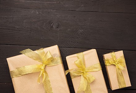 包着棕色纸 绑上金丝带和弓 木本的礼品 庆祝图片