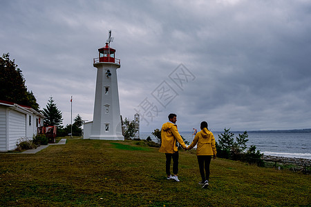 加拿大温哥华岛 加拿大Quadra岛古老历史灯塔 Cape Mudge夫妇在海岸风暴期间穿着黄雨大衣 坎贝尔河 森林图片