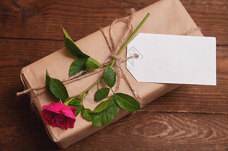 用牛皮纸包裹的礼物 放在与双胞胎绑在一起的花玫瑰上 古董 卡片图片
