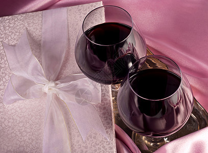 礼物盒 鲜花 酒杯和粉红颜色背景的葡萄酒 婚礼 周年纪念日图片