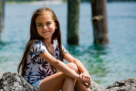 一位可爱的小姑娘坐在阿尔卑斯湖的岸边 在奥地利Plan See湖 周末 快乐的图片