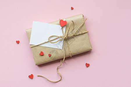 以棕色手工艺纸和领带绳包着的包裹展示在浅粉红色背景上 浪漫礼物 带有装饰红心 顶级视图 爱 二月图片