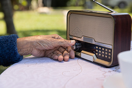 在后院的老式收音机上 高级女性用手把手转弯 幸福的 手指图片