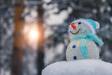 雪人洋娃娃站在雪地漂浮的山上 在阳光破灭的森林背景之下图片