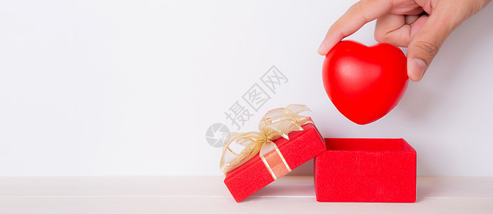情人节 手开红色礼盒放心 庆祝和周年纪念 用心形符号 慈善和健康 复制空间 节日和节日概念捐赠和援助 庆典 丝带图片