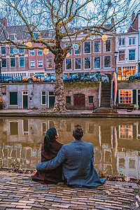 世纪之吻参加城市Utrecht之城之旅的男女夫妇和中年妇女 晚上在荷兰乌得勒支运河旁的夫妇 桥背景