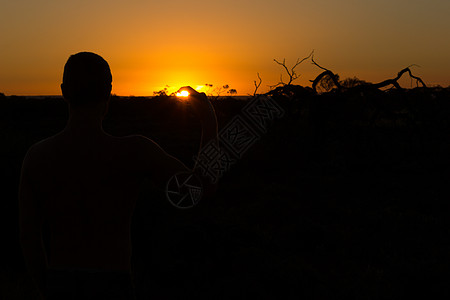 年轻男子日落时在南澳洲外的日落时守着太阳的轮廓图片