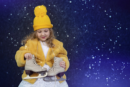 穿着黄皮大衣和带溜冰鞋的毛帽的快乐小女孩图片