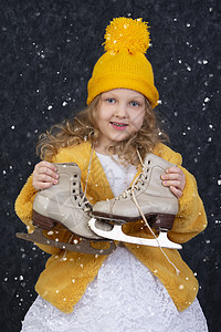 白雪下快乐的小女孩拿着溜冰鞋图片