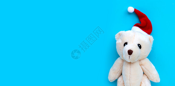 蓝底戴圣塔帽的玩具熊 圣诞假期的概念 笑声 金子 派对图片