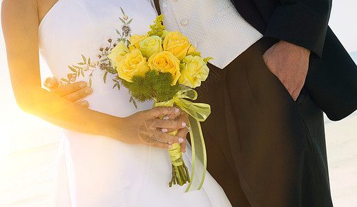 在海滩婚礼上伴着布花的新娘和Groom与Bouquet图片