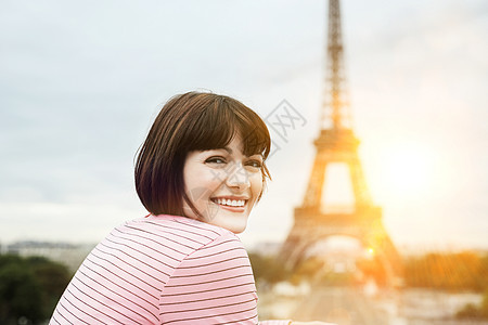 一位快乐的年轻女子在埃菲尔铁塔前微笑的肖像图片