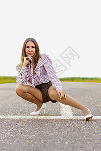 一个女孩坐在跑道上 远处看望着一个阴暗的夏日图片