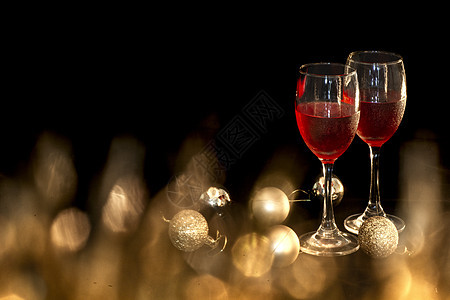 小金黑背景上有两个红酒杯和金色圆球的庆典主题图片