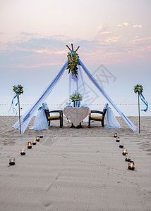 相爱情侣在海沙沙滩沙滩上与蜡烛 灯笼和酒杯共度浪漫晚餐 豪华 庆典图片