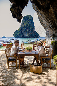 一对中年夫妇在泰国的热带海滩上散步 游客在白色的热带海滩上散步 莱雷海滩背景是长尾船 让游客下车 自然 岛图片