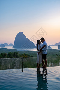 一对中年男女在泰国攀牙湾看日出 攀牙湾观景台 一对夫妇在游泳池边看日出 无边泳池俯瞰泰国攀牙湾 假期 夏天图片