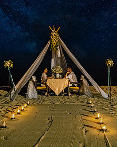 男女情侣在泰国海滩上享用烛光浪漫晚餐 欧洲男人和亚洲女人在海滩情人节概念上共进晚餐 水 蜜月图片