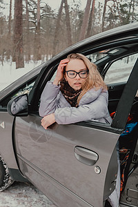 迷人的年轻女性看着车窗外等待旅行和微笑 冬季旅行 坐在车里的女人 寒冷的图片