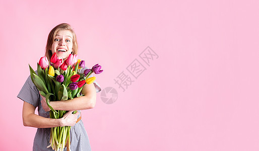 快乐的年轻女子拿着鲜丽郁金香花束 与粉红背景隔绝图片