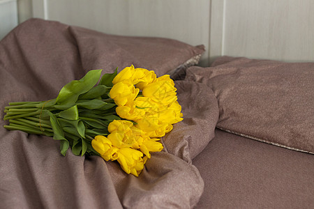 床上有一束黄色的郁金香 新鲜的郁金香花束 在卧室内部的春天花 春天或假期的概念 3 月 8 日 国际妇女节 自然 生日图片