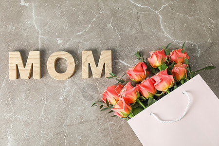 装满花束橙色玫瑰的礼品袋 并将妈妈刻在棕色背景上 顶层风景 植物群 字母图片