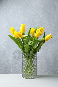 木桌玻璃花瓶中美丽的黄色郁金香图片