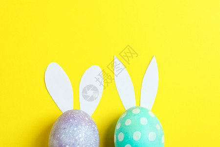 装饰复活节鸡蛋 黄色背景上有可爱的兔子耳朵 花朵 团体图片