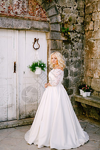新娘站在一个旧砖楼前 在Perast的一扇白木门和花盆旁边背景图片