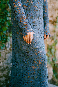 穿着时装的蓝色蓝蕾丝裙的女人手站立 墙壁与常春藤连在一起 紧贴近身图片