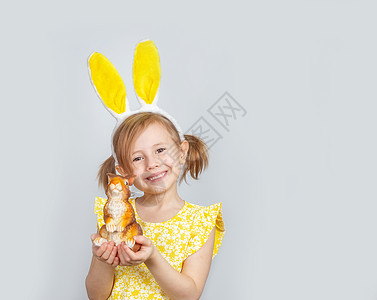 小白种女孩穿着黄色礼服和兔子耳朵 摆在平底背景上 快乐的 快乐图片